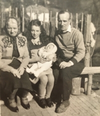 Marie Hlídková with her husband Zbynek Hlídek, their child and her mother Maria Svobodová on a bench in front of the house in Stribrna Skalice