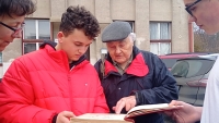 Jan Horáček shows the team from ZŠ Chrastava the chronicle of the company TOTEX, to which he contributed, 2022