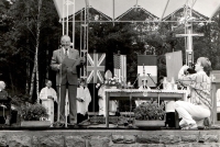 První pietní shromáždění v roce 1990 na výročí vypálení obce Ležáky. Na pódiu pronáší řeč herec Radovan Lukavský 