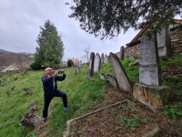 George Drost taking a photo of a gravestone of his relatives at the Jewish cemetery in Lomnice, 2024