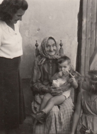 Approximately in 1952-53 in Malechov, in the yard of Jiří's great-grandmother Anna Hodanová holds little Jiří Hodan, a future musician who tragically died in a plane crash in 1973 (Aeroflot Flight 141). Next to him sits his older sister (Jiri Podlipny's mother) and above them in a white blouse stands Jiri's grandmother Květoslava Hodanová, née Kašparová