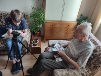 František Outrata looking at photos from his life while recording an interview for the Stories of Our Neighbours project