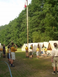 Morning flag-raising ceremony - all camp participant are wearing scout uniforms, the flag is being raised by flag guards, Dědov, the present day